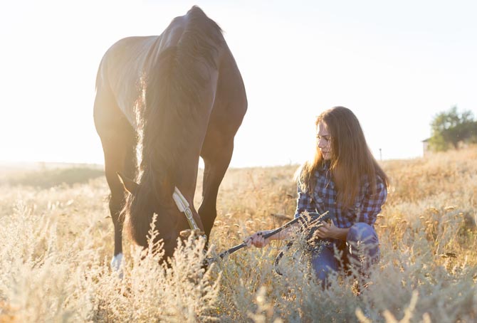 Eine Frau sitzt mit ihrem Pferd in einem Getreidefeld